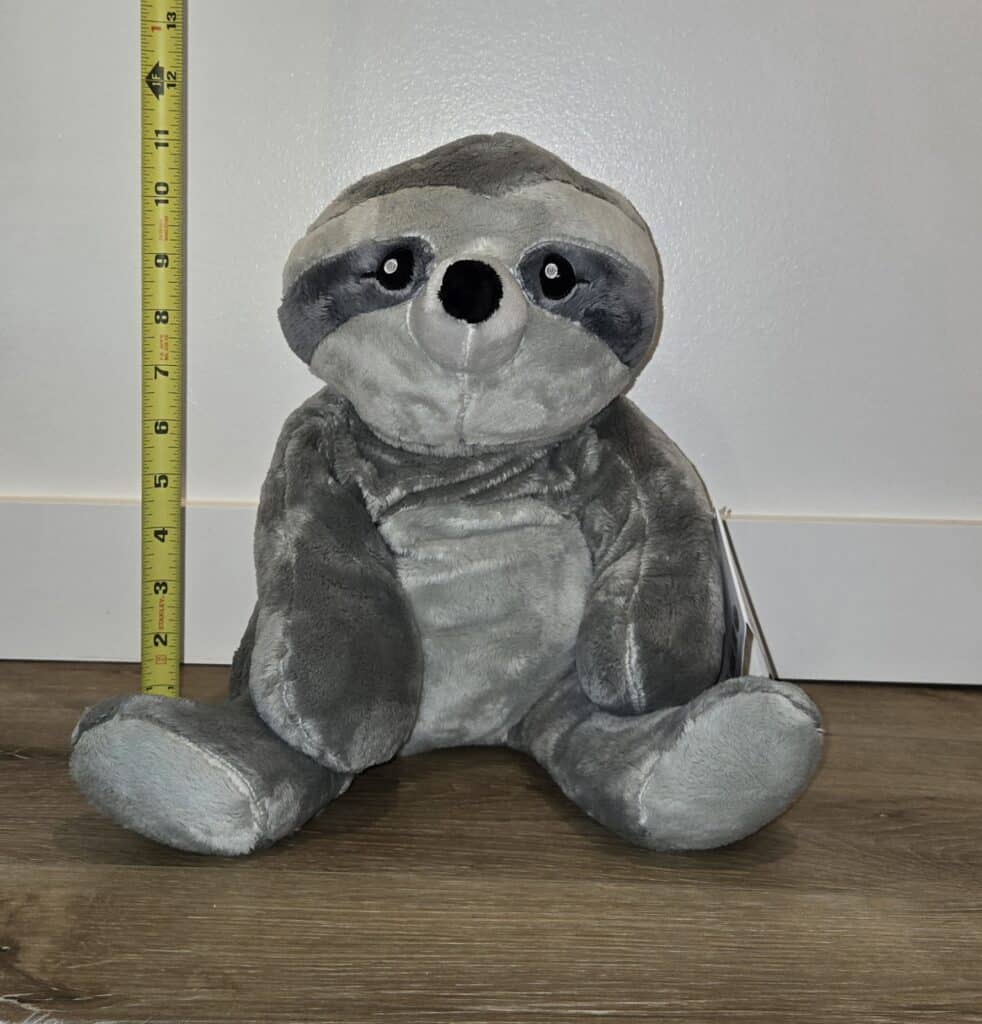 Sam the Sloth, a weighted plush toy, being measured to demonstrate its size and use as a comforting weighted blanket alternative
