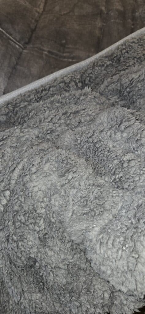 A close-up of the thick, gray, Cottonblue Sherpa weighted blanket, highlighting its cozy and plush shaggy texture.