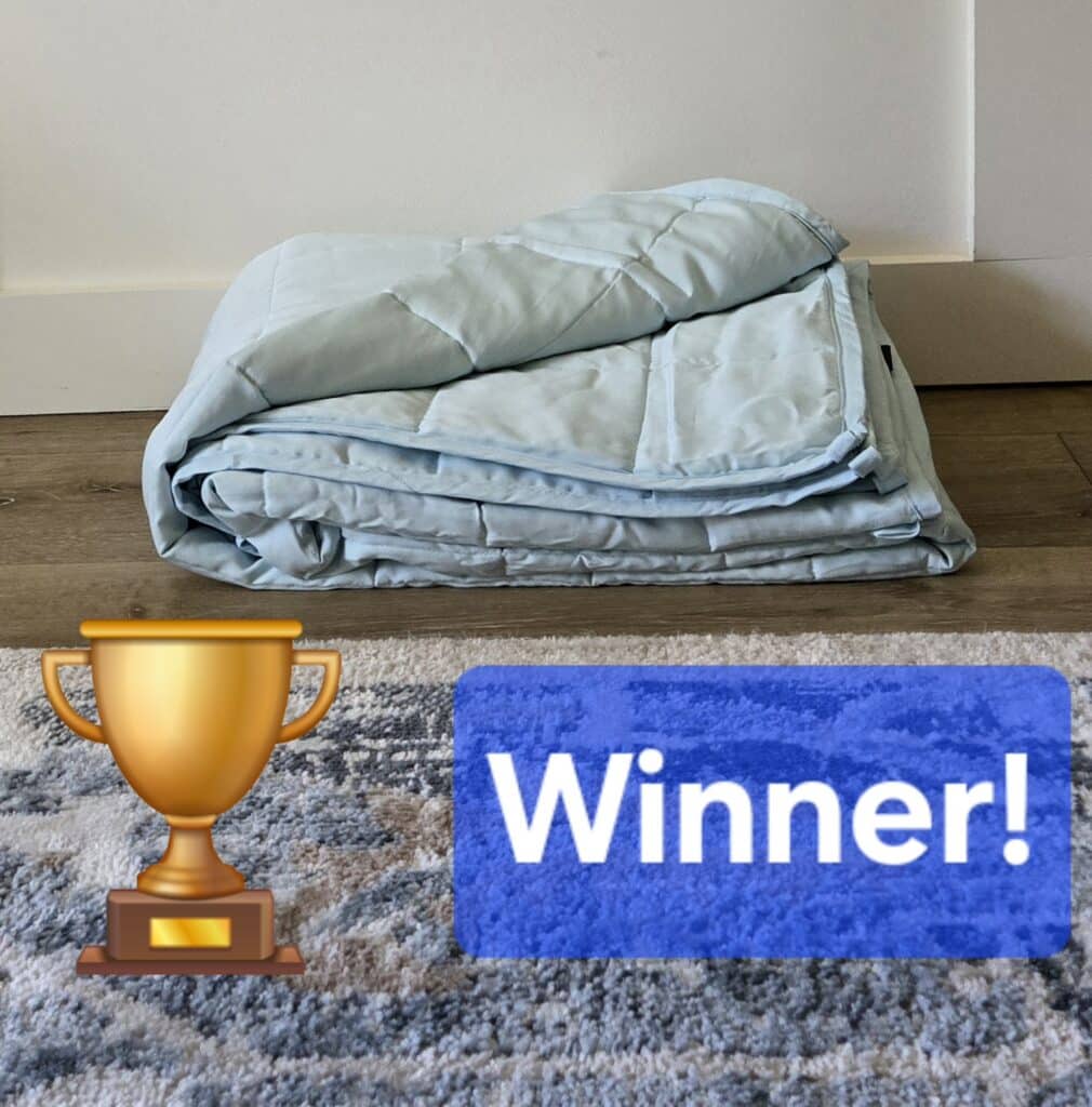 A neatly folded blue YnM weighted blanket, showing its smooth fabric and classic square-stitched pattern.